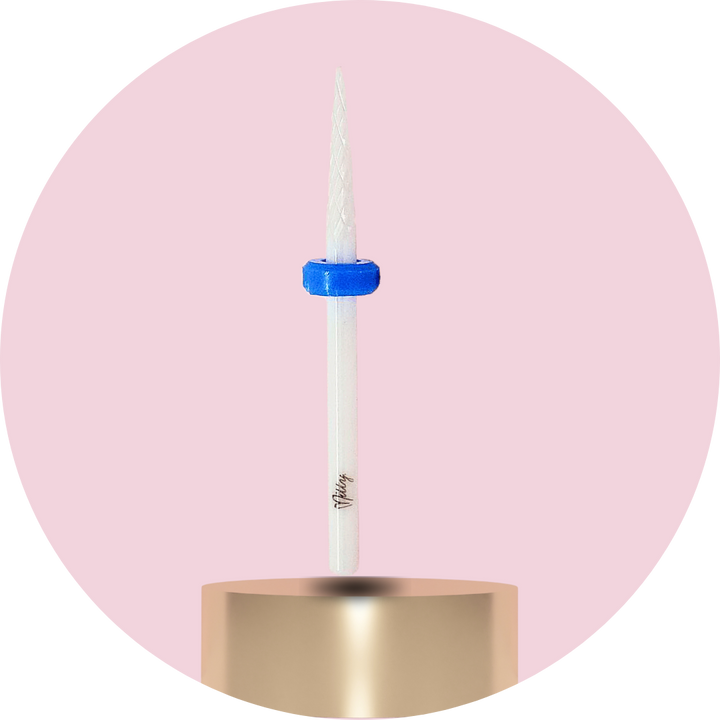 Candle with a blue wick holder on a gold base against a pink background